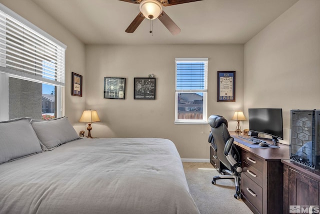 bedroom featuring light carpet, baseboards, an office area, and ceiling fan