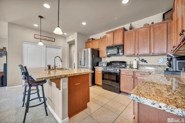 kitchen with black appliances, a sink, recessed lighting, pendant lighting, and a kitchen island with sink