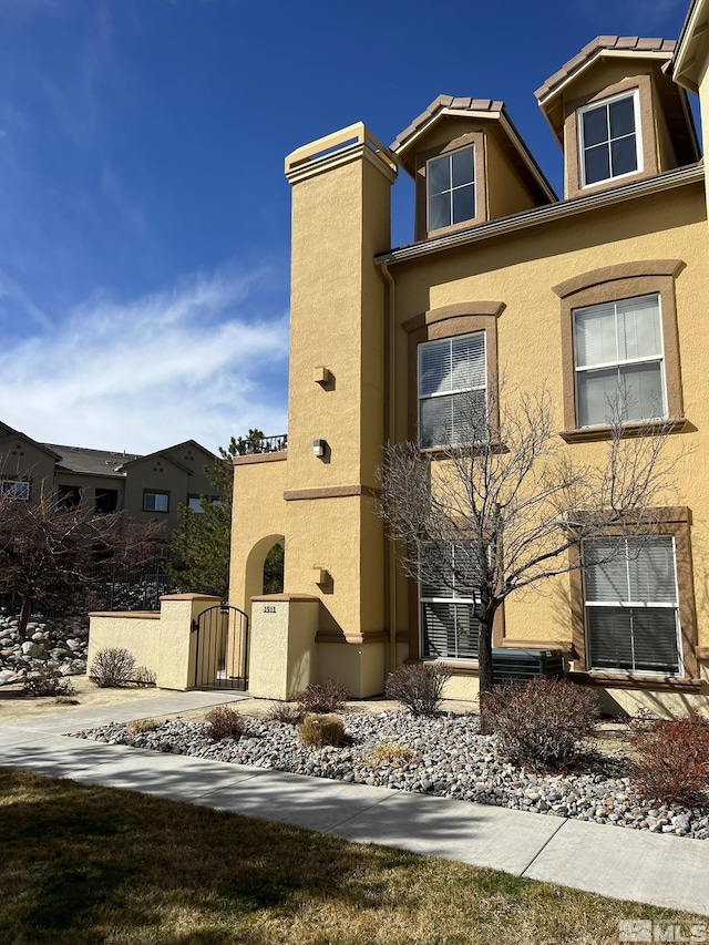 view of front facade featuring stucco siding and a gate