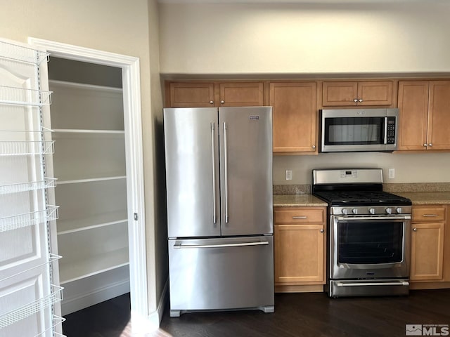 kitchen with appliances with stainless steel finishes, dark wood finished floors, brown cabinets, and light stone counters