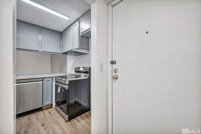 kitchen with appliances with stainless steel finishes, gray cabinets, light wood-style flooring, and light countertops