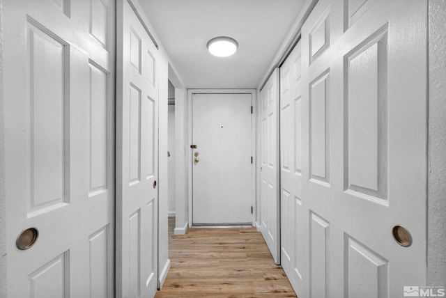 corridor featuring light wood-style floors and baseboards