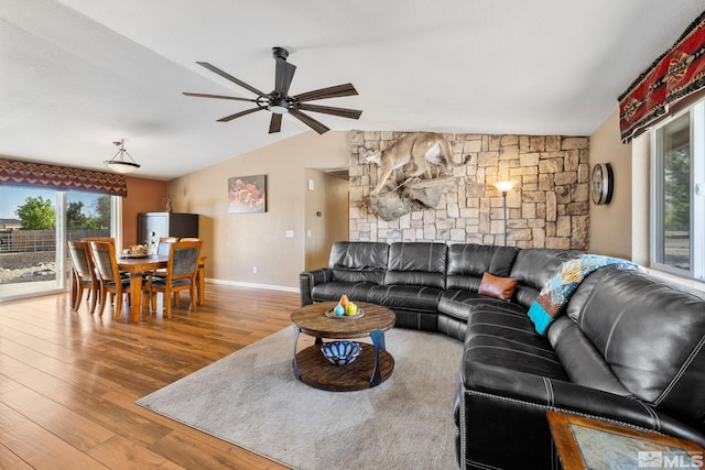 living room with healthy amount of natural light, lofted ceiling, wood finished floors, ceiling fan, and baseboards