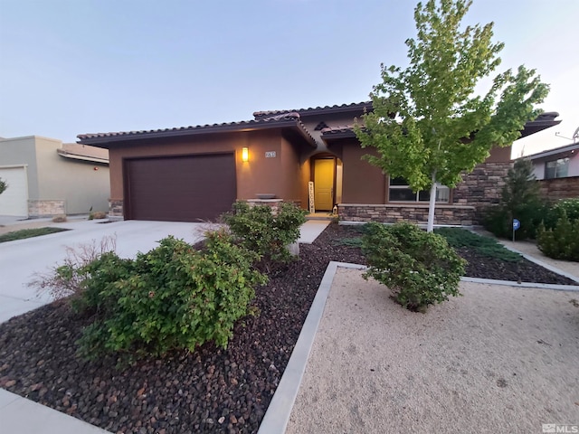 view of front of house with stone siding, stucco siding, a garage, and concrete driveway