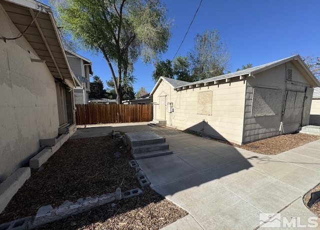 view of home's exterior with fence, a patio area, and concrete block siding