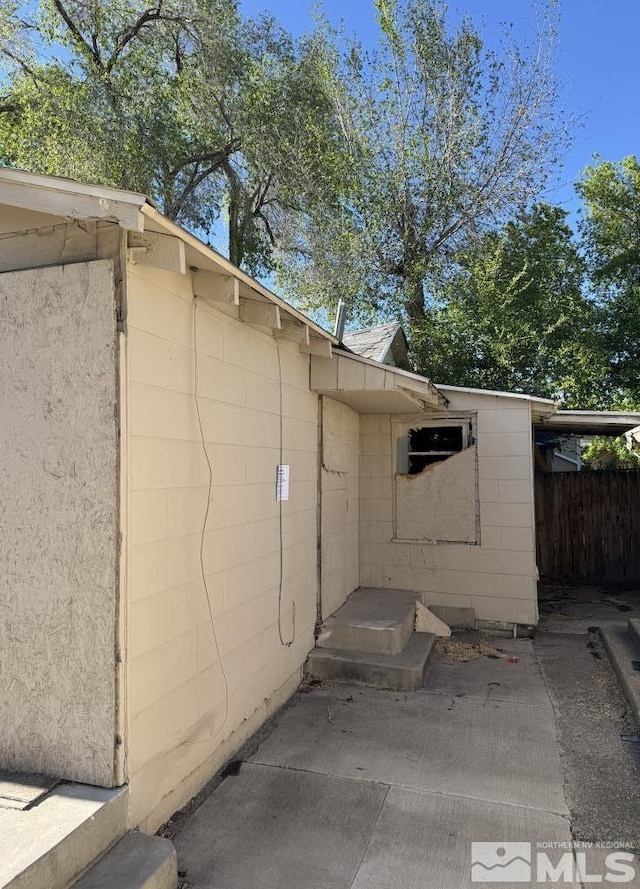 view of home's exterior featuring concrete block siding and fence