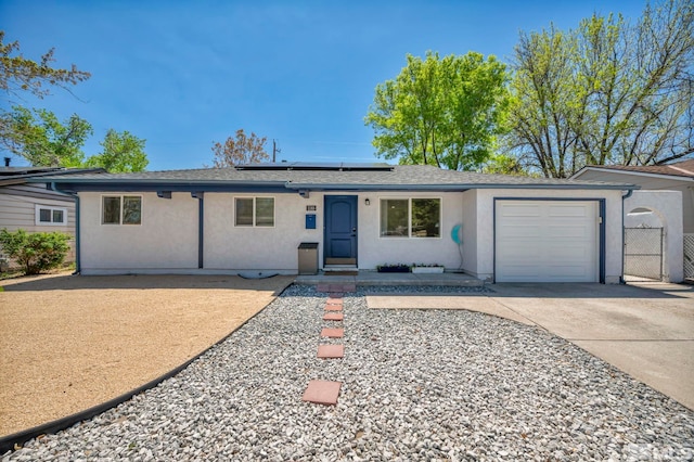 ranch-style home featuring stucco siding, concrete driveway, an attached garage, roof mounted solar panels, and fence