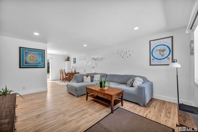 living area featuring baseboards, light wood finished floors, and recessed lighting