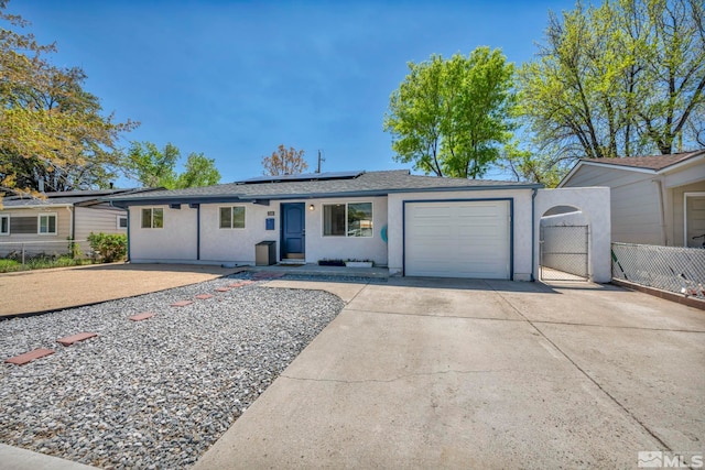 ranch-style home featuring stucco siding, a garage, concrete driveway, fence, and solar panels