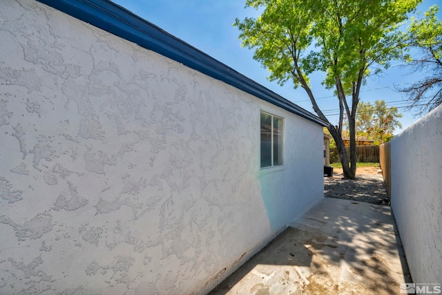 view of side of property featuring fence and stucco siding