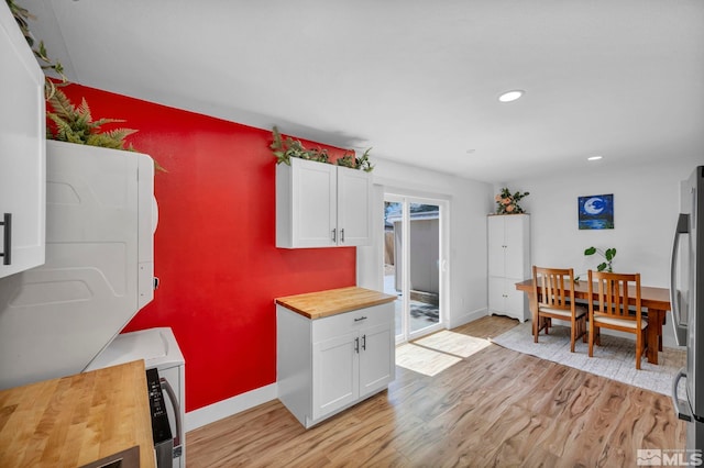 kitchen featuring butcher block countertops, light wood finished floors, white cabinets, freestanding refrigerator, and recessed lighting