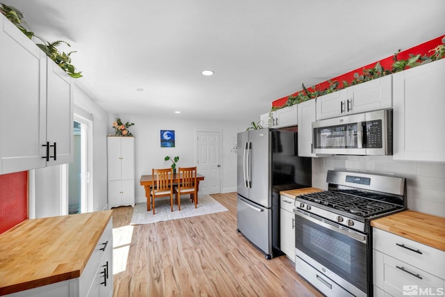 kitchen with butcher block countertops, appliances with stainless steel finishes, light wood-style floors, recessed lighting, and white cabinets