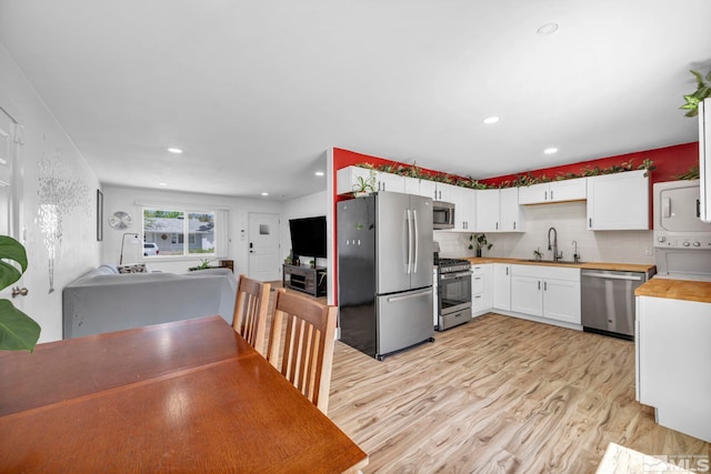 kitchen with appliances with stainless steel finishes, a sink, stacked washer / dryer, wood counters, and decorative backsplash