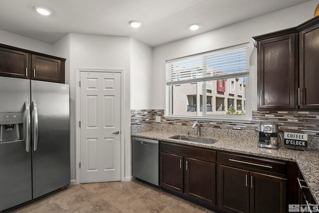 kitchen featuring appliances with stainless steel finishes, a sink, decorative backsplash, and dark brown cabinets