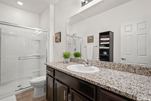 bathroom featuring a shower stall, toilet, vanity, and tile patterned flooring