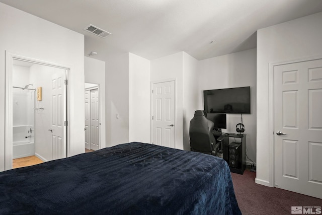 carpeted bedroom featuring baseboards, a desk, and ensuite bath