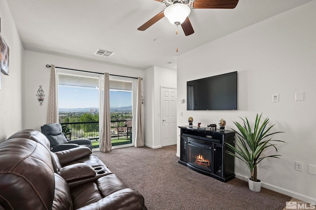 living room with carpet, baseboards, a glass covered fireplace, and a ceiling fan