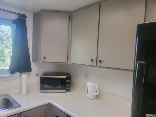 kitchen featuring black fridge, gray cabinets, light countertops, and plenty of natural light