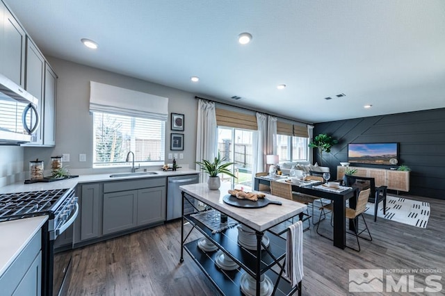 kitchen featuring a sink, appliances with stainless steel finishes, gray cabinets, dark wood-type flooring, and light countertops
