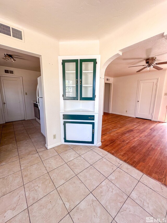 unfurnished room featuring light tile patterned floors, arched walkways, a ceiling fan, and baseboards