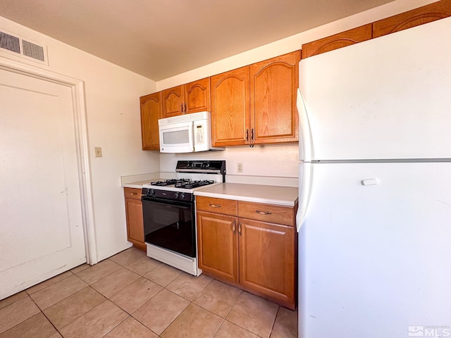 kitchen featuring white appliances, light countertops, light tile patterned floors, and brown cabinets
