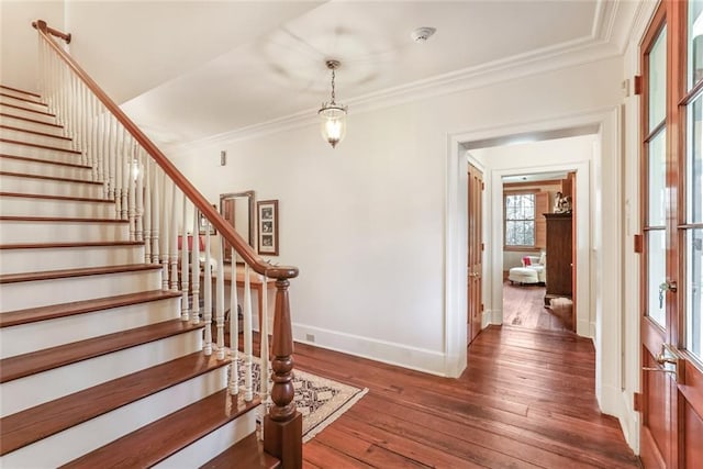 stairway with ornamental molding and dark hardwood / wood-style floors