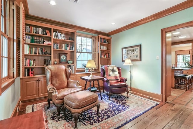 sitting room featuring crown molding, wood-type flooring, and a healthy amount of sunlight