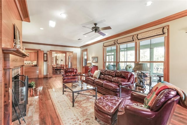 living room featuring ornamental molding, ceiling fan, hardwood / wood-style flooring, and a fireplace