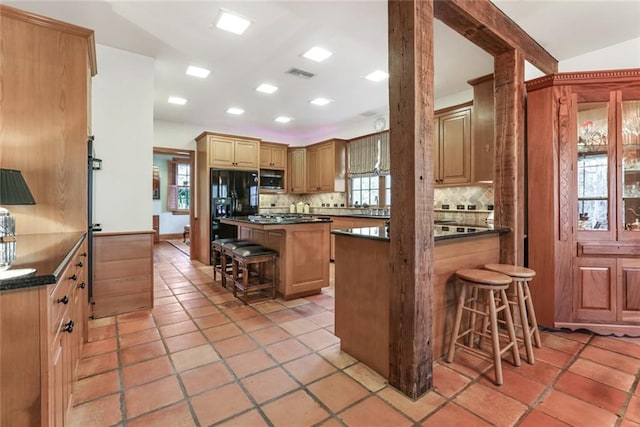 kitchen featuring a breakfast bar, built in microwave, tasteful backsplash, and light tile flooring