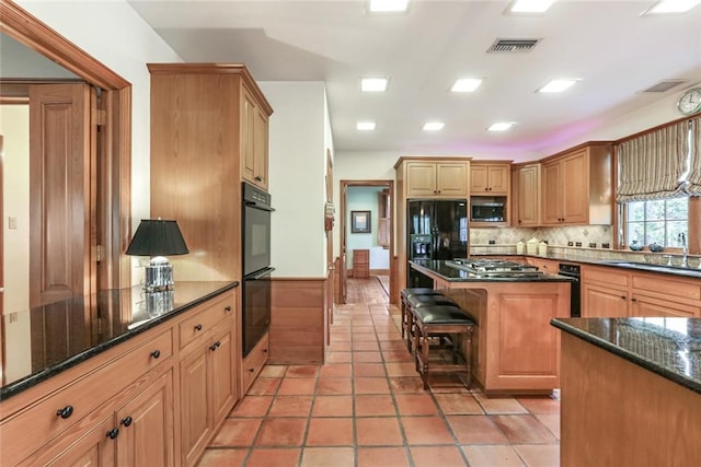 kitchen featuring sink, light tile floors, dark stone countertops, backsplash, and black appliances