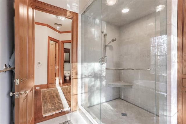 bathroom with tile floors, a shower with door, ornamental molding, and toilet