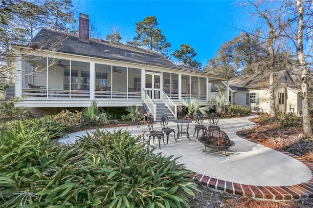 rear view of property featuring a fire pit, a sunroom, and a patio