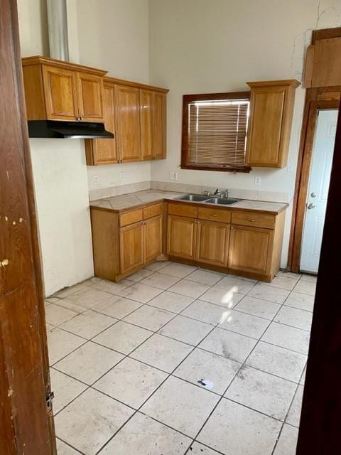 kitchen featuring sink, light tile floors, and a towering ceiling