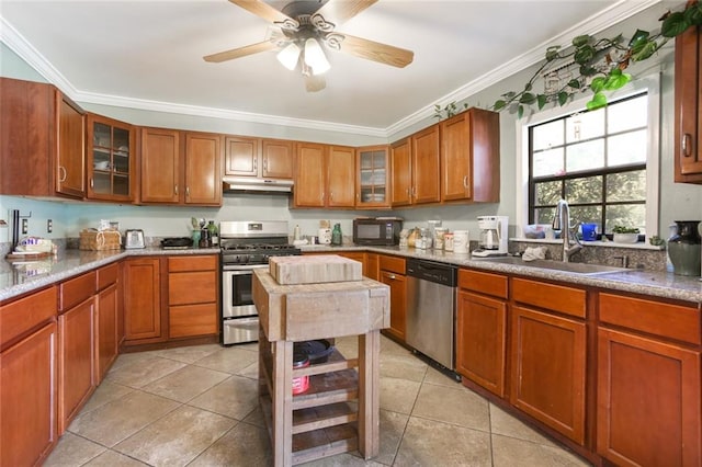 kitchen with ceiling fan, light tile floors, sink, ornamental molding, and appliances with stainless steel finishes