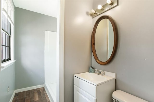 bathroom featuring toilet, wood-type flooring, and vanity with extensive cabinet space