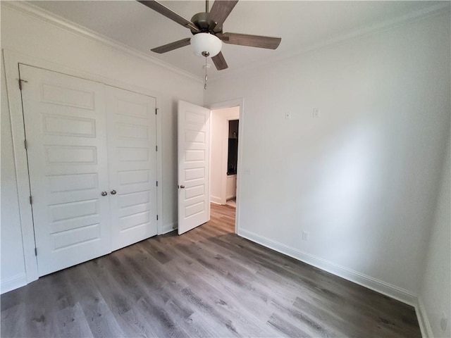 unfurnished bedroom with a closet, ceiling fan, crown molding, and dark wood-type flooring