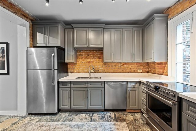 kitchen with dark tile floors, stainless steel appliances, gray cabinets, and sink