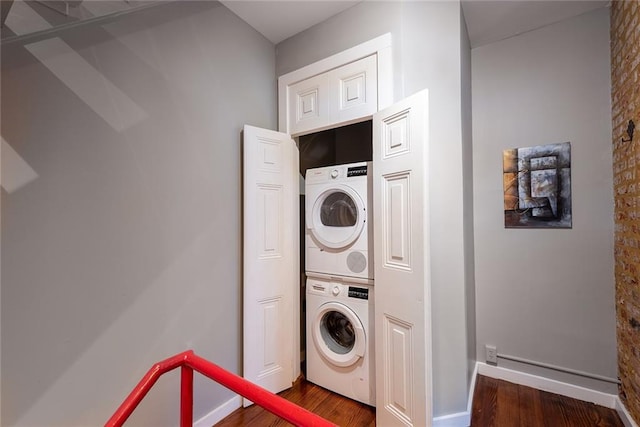 laundry area with stacked washer / drying machine and dark hardwood / wood-style flooring