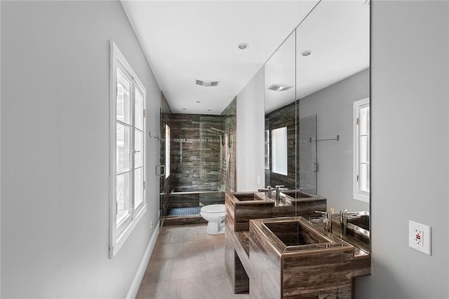 bathroom featuring toilet, tile floors, tiled shower, and dual vanity