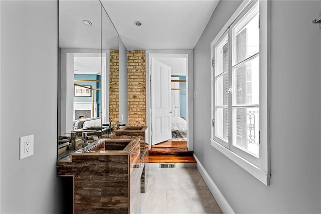 bathroom featuring brick wall, vanity, and tile flooring