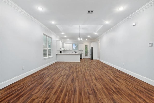 unfurnished living room with an inviting chandelier, hardwood / wood-style floors, ornamental molding, and a tray ceiling