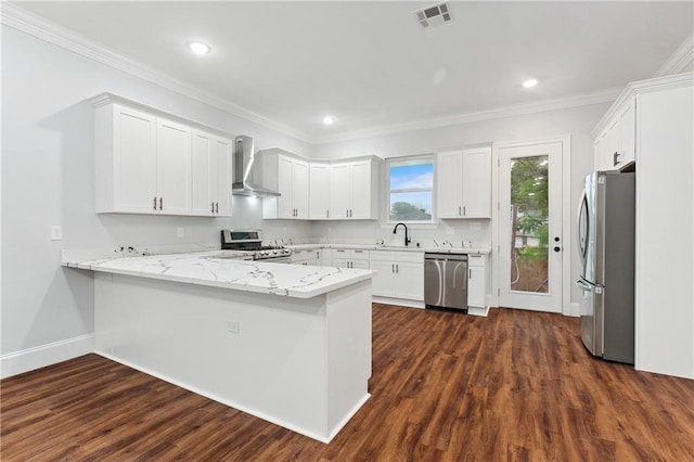 kitchen featuring appliances with stainless steel finishes, kitchen peninsula, wall chimney range hood, and dark hardwood / wood-style flooring