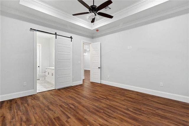 unfurnished bedroom featuring a barn door, ceiling fan, and hardwood / wood-style flooring