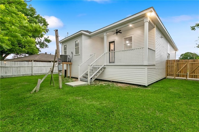 rear view of property featuring ceiling fan and a yard