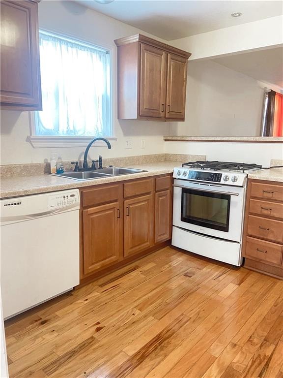 kitchen with white appliances, sink, and light wood-type flooring