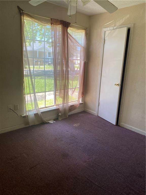 unfurnished room with dark carpet and ceiling fan