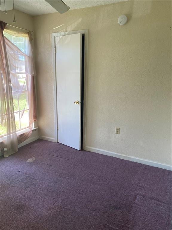 carpeted empty room with ceiling fan and a textured ceiling