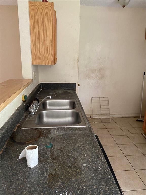 kitchen featuring sink, light tile floors, and dark stone countertops