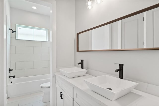 full bathroom featuring double vanity, toilet, tile floors, and tiled shower / bath