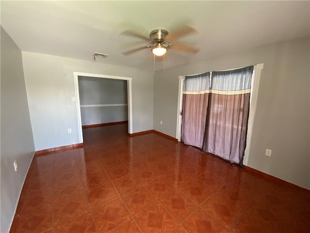 unfurnished room with dark tile floors and ceiling fan